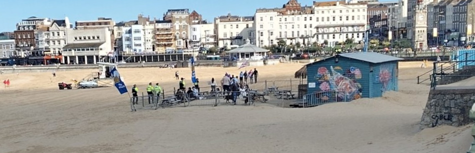 all 8 UKIP supporters running away across Margate beach accompanied by police officers.